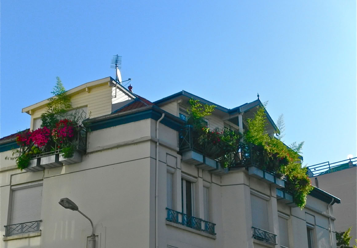 Maison avec beaucoup de végétation dans les jardinières au dernier étage.